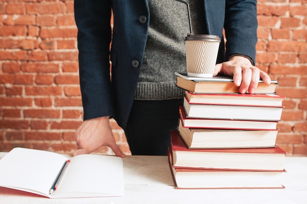 Estudiante cerca de una pila de libros y una taza de café