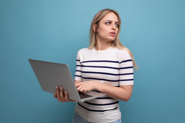 Estudiante chica inteligente con una computadora portátil en sus manos sobre un fondo azul aislado