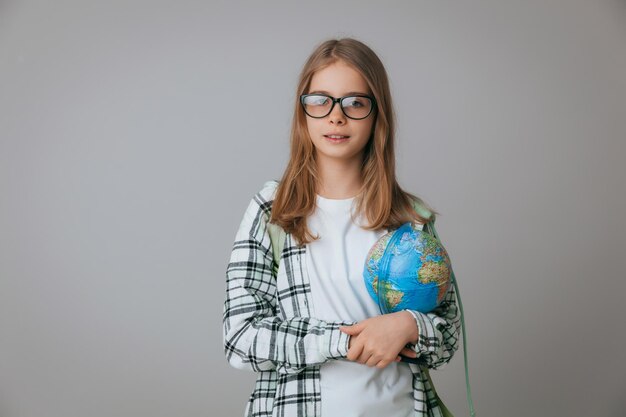 Estudiante de colegiala adolescente caucásica sosteniendo un globo sobre un fondo gris aislado Feliz día de la tierra