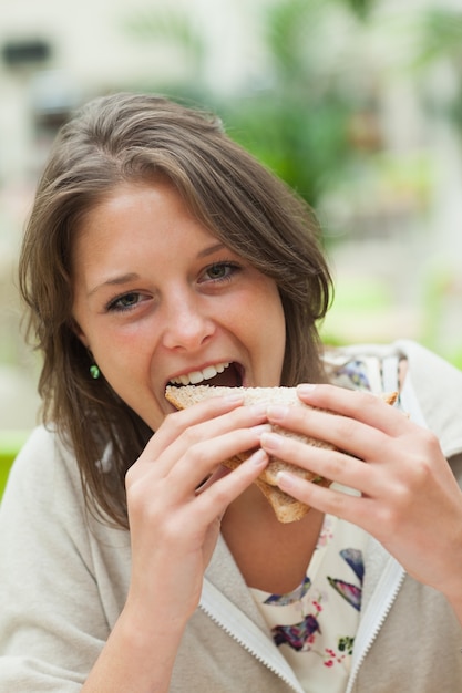 Estudiante comiendo sándwich en la cafetería