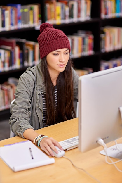 Estudiante y computadora para el estudio y la investigación de cursos en línea con bloc de notas de papel en la biblioteca de la universidad Aprendizaje a distancia de persona femenina y clase virtual para tecnología de acceso a Internet y lección remota