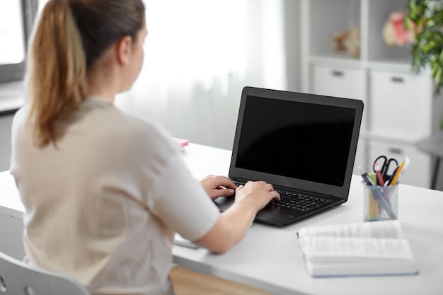 estudiante con una computadora portátil y un libro en casa