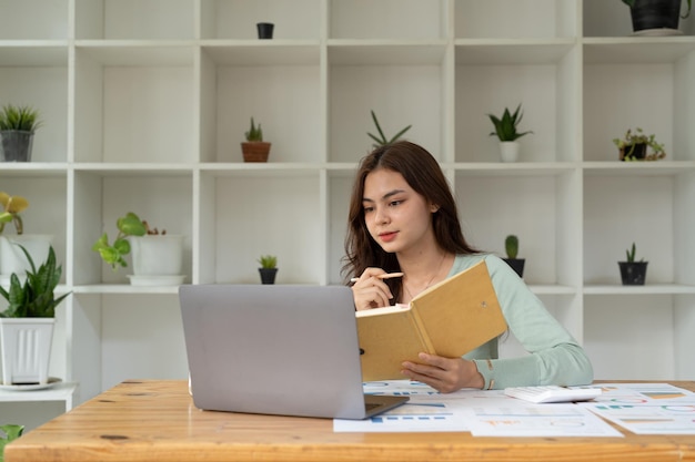 Estudiante concentrada ocupada estudiando usando una computadora portátil, toma notas en un cuaderno, un trabajador hombre enfocado, un empleado, escribe viendo un seminario web o un curso de capacitación en línea sobre el concepto de educación informática