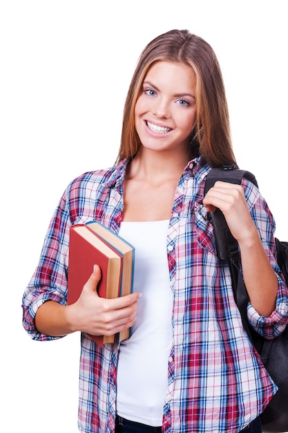 Estudiante confiado. Hermosas mujeres jóvenes con libros llevando mochila y mirando a la cámara