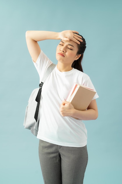 Estudiante confundido mano a frente facepalm gesto sostiene libros no preparados para exámenes