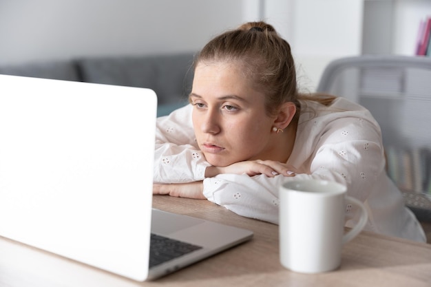 Estudiante deprimida cansada y aburrida frente a la computadora portátil durante la clase virtual