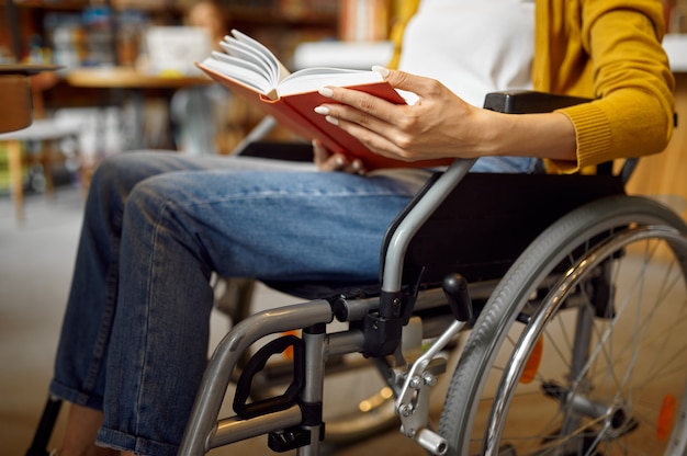 Estudiante discapacitado en silla de ruedas leyendo un libro