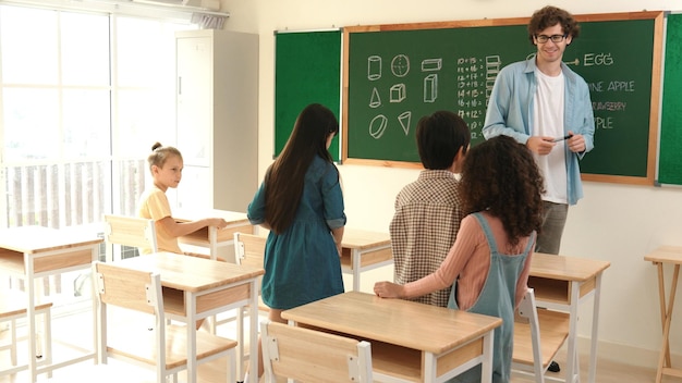 Estudiante diverso caminando en el aula mientras el maestro mira al niño Pedagogía