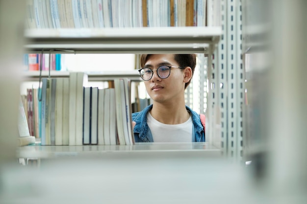 Estudiante eligiendo y leyendo un libro en la biblioteca