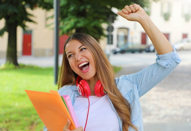 Estudiante emocionada sosteniendo cuadernos