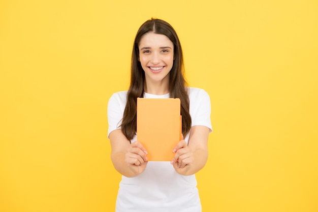 Estudiante encantador aislado sobre fondo de color amarillo Mujer estudiante de secundaria mantenga cuadernos Educación en concepto de colegio universitario de escuela secundaria