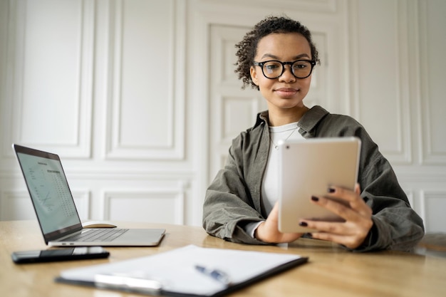 Estudiante encantadora comunicación por video computadora mujer gafas rizadas aprendizaje en línea computadora portátil oficina