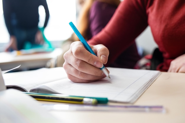 Un estudiante escribe en una hoja de papel con un lápiz.