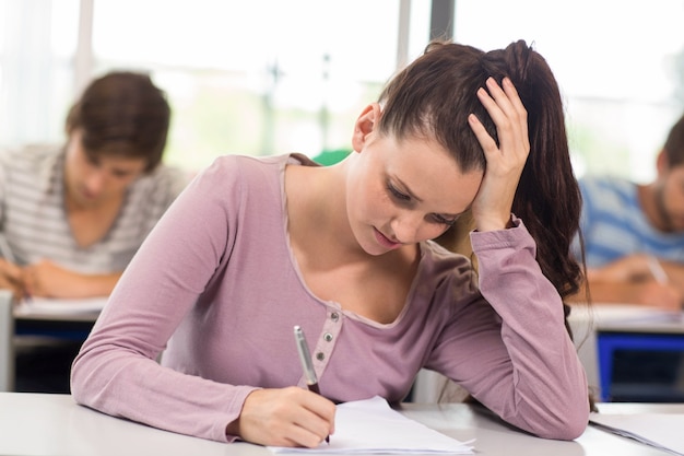 Estudiante escribiendo notas en el aula