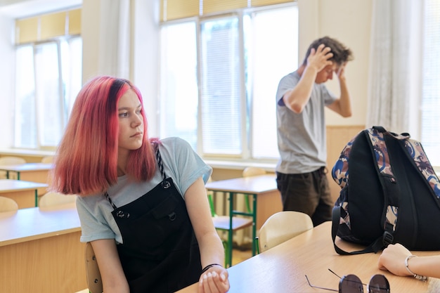 Estudiante de la escuela de moda chica adolescente en el aula, chica seria de 16 años mira hacia el lado sentado en el escritorio durante el descanso entre lecciones