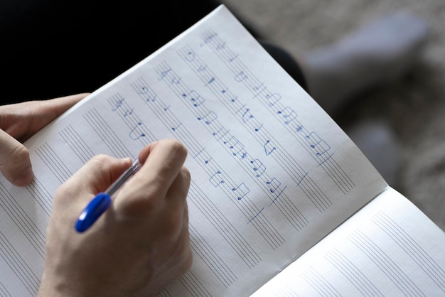 Un estudiante de la escuela de música escribe notas musicales en un cuaderno