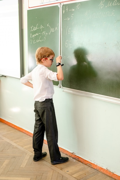 Estudiante de escuela primaria escribiendo respuestas de matemáticas en la pizarra