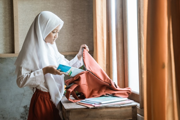 Estudiante de la escuela primaria de Indonesia preparando su libro en casa antes de ir a la escuela por la mañana