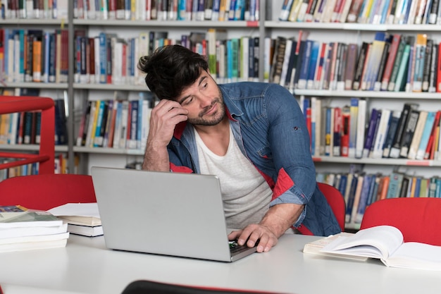 Estudiante estresado en la escuela secundaria sentado en el escritorio de la biblioteca