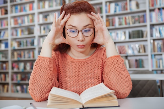 Estudiante estresado por un libro en la biblioteca