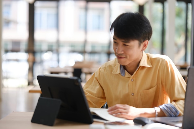 Estudiante estudiando en línea y preparándose para exámenes con dispositivos y libros digitales