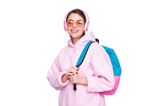 Estudiante feliz con capucha rosa casual escuchando auriculares con mochila escolar aislada en blanco