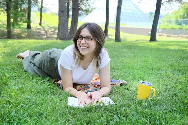 Una estudiante feliz descansa en un parque sobre un césped