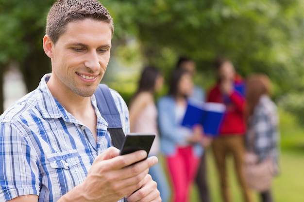 Estudiante feliz enviando un texto afuera en el campus