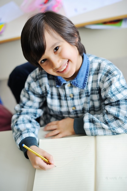 Estudiante feliz escribiendo en el cuaderno en el aula de la escuela