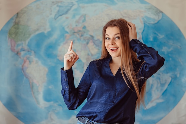 Estudiante feliz con un mapa del mundo en la pared