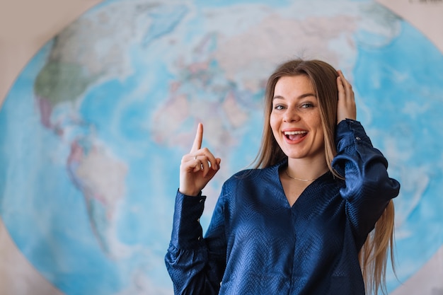 Estudiante feliz con un mapa del mundo en la pared