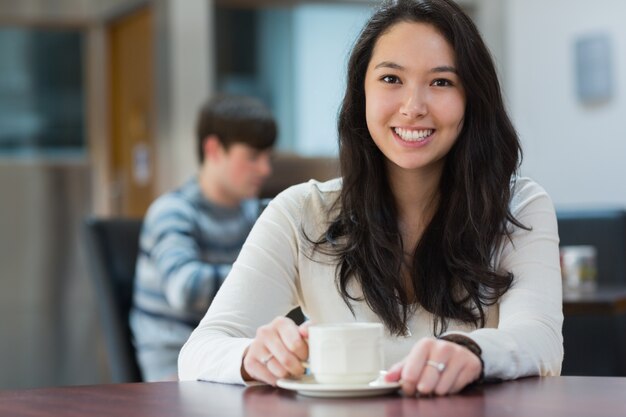 Estudiante feliz sentado en una cafetería