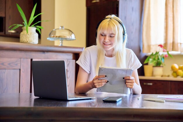 Estudiante femenina en auriculares usando una computadora portátil estudiando en casa