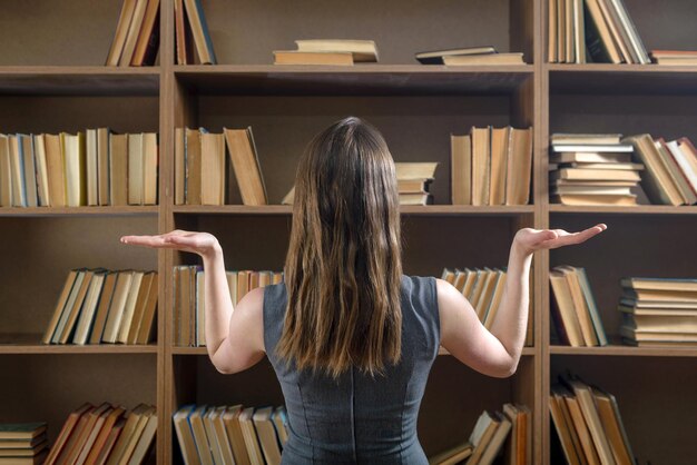 Estudiante femenina elige un libro de una librería en la biblioteca