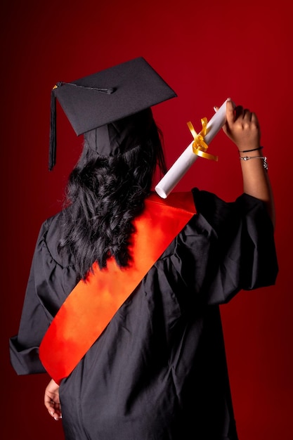 Estudiante femenina en una foto de graduación Título de fin de educación con diploma de posgrado Túnica universitaria con sombrero en la espalda con el diploma