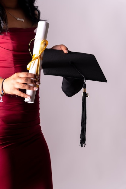 Estudiante femenina en una foto de graduación Título de fin de educación con diploma de posgrado Universidad en túnica negra sosteniendo el diploma con la mano y con el sombrero