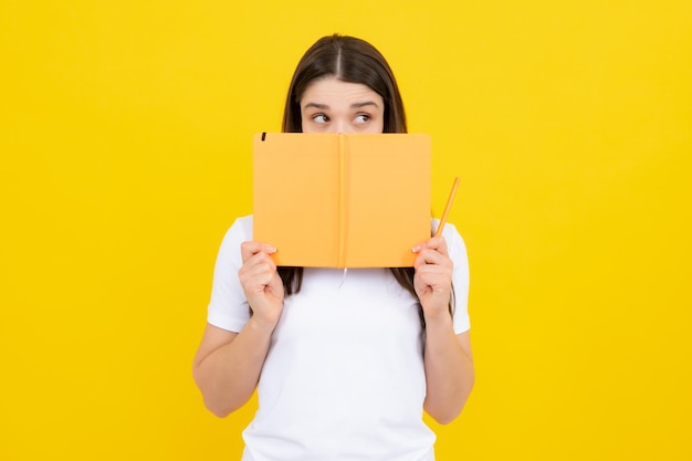 Estudiante femenina tiene libros aislados sobre fondo amarillo en la escuela de inglés de estudio