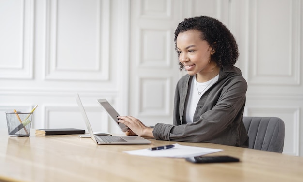 Estudiante femenina usa el lugar de trabajo de la computadora portátil en el espacio de coworking aprendizaje en línea trabajando con documentos