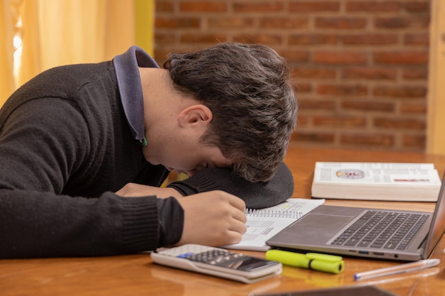 Estudiante frustrado estudiando frente a una computadora portátil
