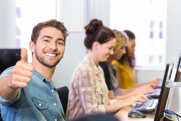 Estudiante gesticulando pulgares arriba en clase de informática