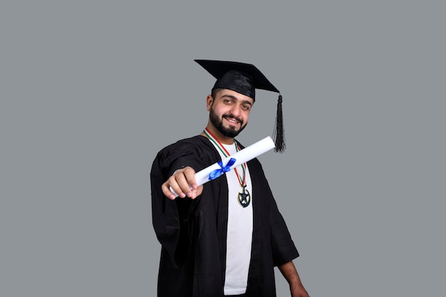 Foto estudiante graduado feliz con un diploma en la mano modelo paquistaní indio