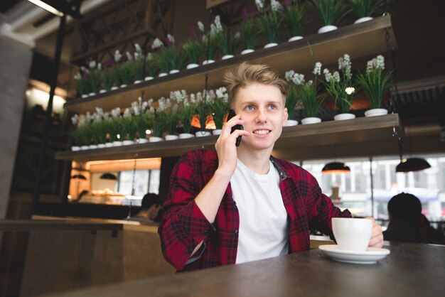 Un estudiante habla por teléfono en el café y sonríe.