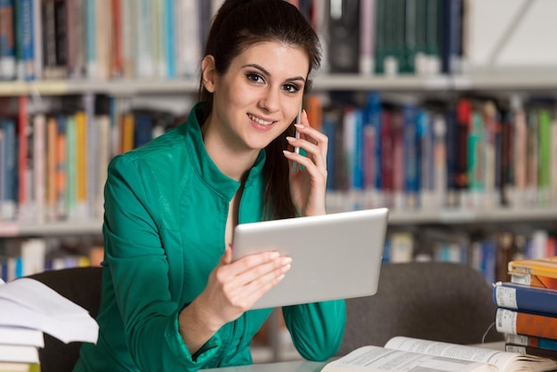 Estudiante hablando por teléfono en la biblioteca con poca profundidad de campo.