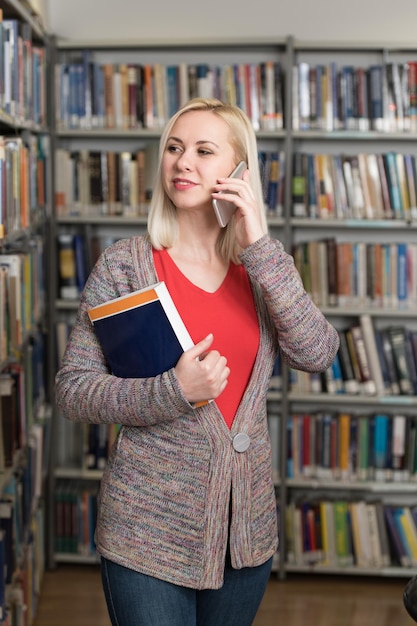 Estudiante hablando por teléfono en la biblioteca de la Universidad