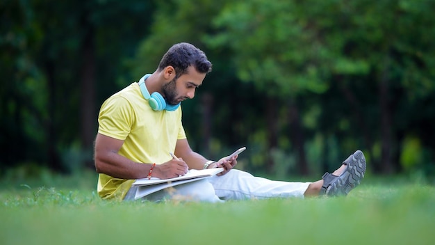 Un estudiante haciendo un dibujo mirando el móvil