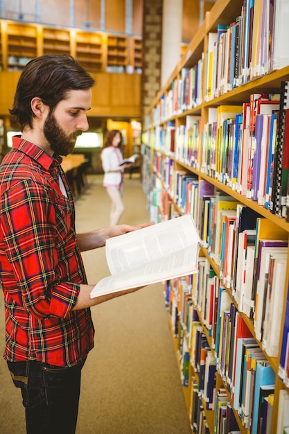Estudiante Hipster escoger un libro en la biblioteca