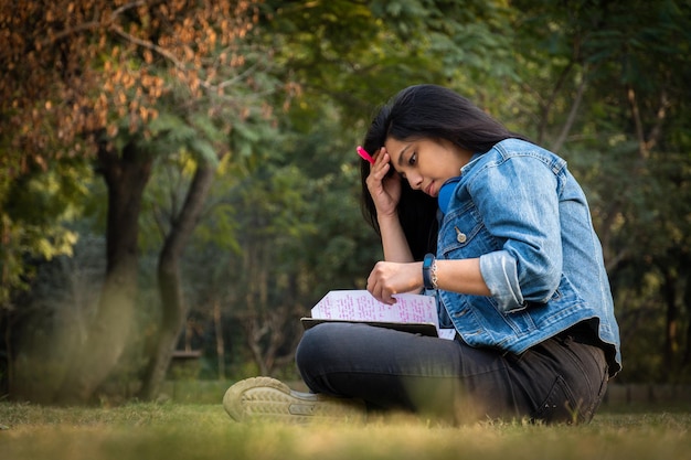 Estudiante indio en el campus universitario de imagen de tamaño completo leyendo libros y mirando la cámara