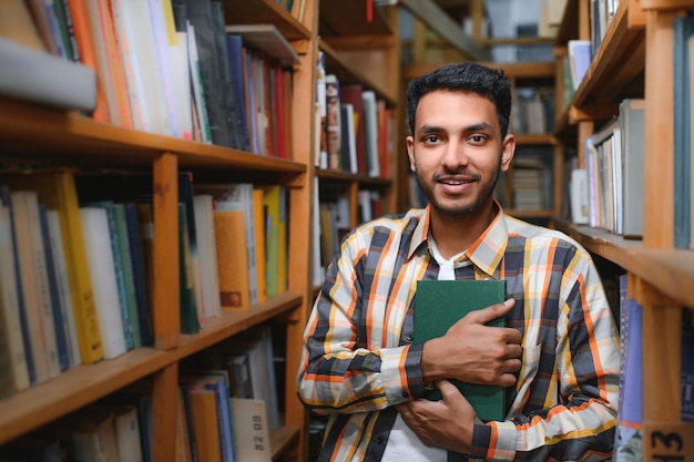 Estudiante indio masculino en la biblioteca con libro