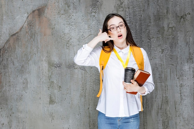 Estudiante inteligente con gafas sosteniendo un libro y una taza de café. foto de alta calidad