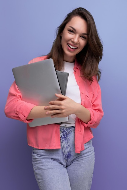 Estudiante inteligente morena joven en camisa y jeans con laptop